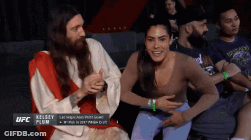 A Man Dressed As Jesus Is Sitting Next To A Woman Who Is Smiling GIF