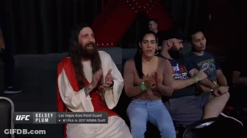 A Man Dressed As Jesus Talks To A Woman In A Crowd GIF