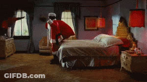 A Man Dressed As Santa Claus Is Standing On Top Of A Bed GIF