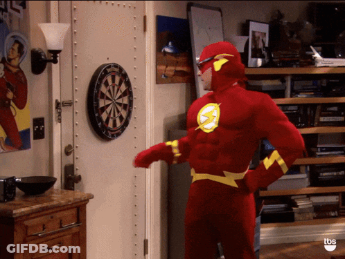 A Man Dressed As The Flash Stands In Front Of A Dart Board GIF
