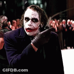 A Man Dressed As The Joker Is Standing In Front Of A Crowd Of People GIF