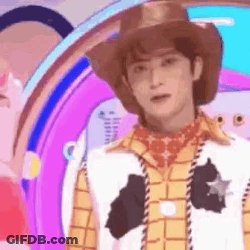 A Man Dressed As Woody From Toy Story Is Standing In Front Of A Purple Background . GIF