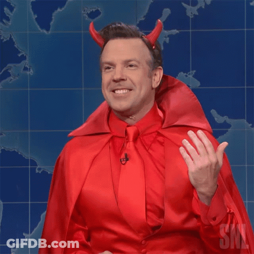 A Man Dressed In A Devil Costume With Horns And A Cape Is Waving GIF