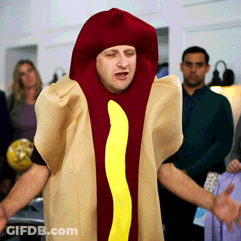 A Man Dressed In A Hot Dog Costume With A Yellow Sausage GIF