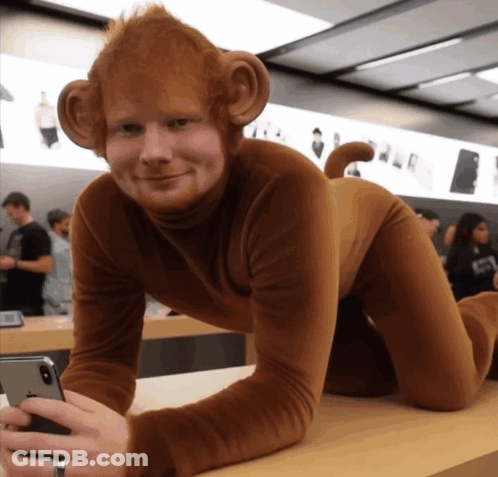A Man Dressed In A Monkey Costume Holds A Cell Phone GIF