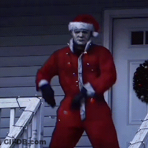 A Man Dressed In A Santa Suit Is Standing On A Porch GIF