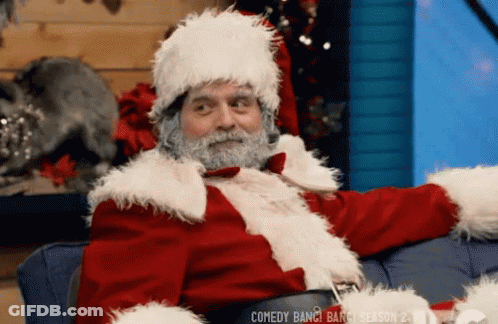 A Man Dressed Up As Santa Claus Is Sitting On A Couch GIF