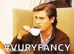 A Man Drinking A Cup Of Coffee With The Words #Vuryfancy Written Below Him GIF