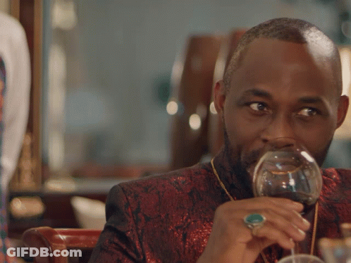 A Man Drinking A Glass Of Wine With The Words Plots Silently Below Him GIF