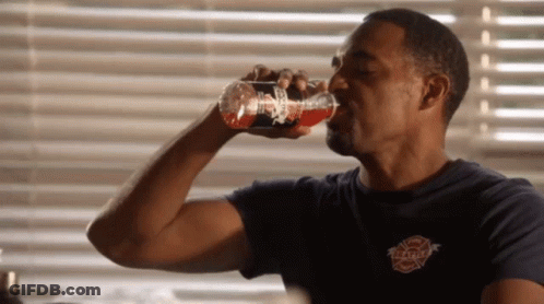 A Man Drinking From A Bottle That Says Firefighter GIF