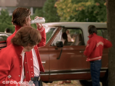 A Man Drinking From A Bottle While Wearing A Red Jacket That Says ' Columbia ' On It GIF