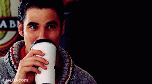 A Man Drinking From A Cup With A Sign Behind Him That Says A Be GIF