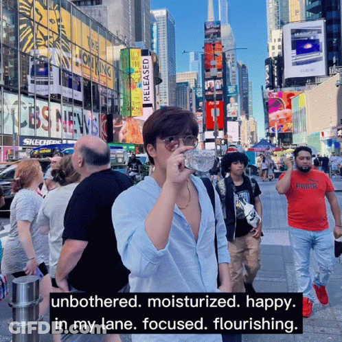 A Man Drinking Water From A Bottle In A Crowded City GIF