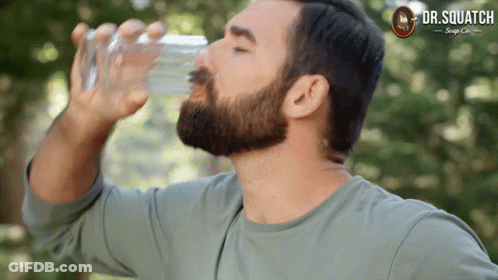A Man Drinking Water From A Glass With A Dr. Squatch Logo On The Bottom GIF