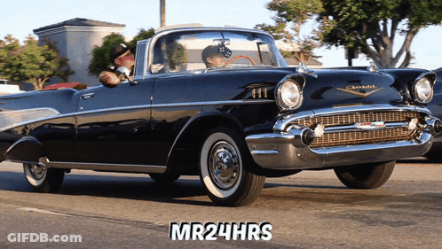 A Man Driving A Black Chevrolet With The Words Mr24hrs On The Bottom GIF