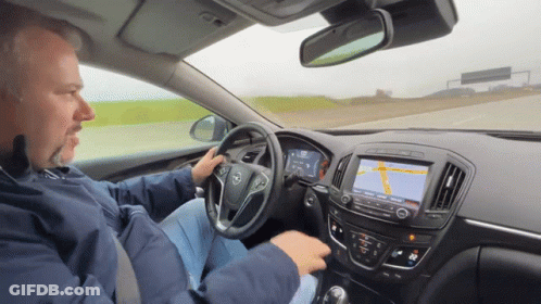 A Man Driving A Car With A Map On The Dashboard GIF