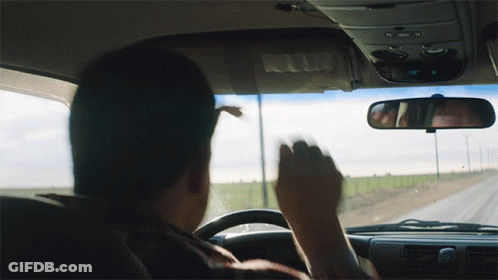 A Man Driving A Car With A Rear View Mirror That Says ' Passenger ' On It GIF