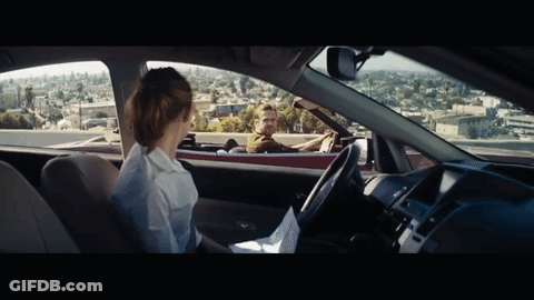 A Man Driving A Red Convertible With A Woman Sitting In The Back Seat GIF