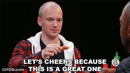 A Man Eating A Chicken Wing With The Words Let 'S Cheers Because This Is A Great One Above Him GIF