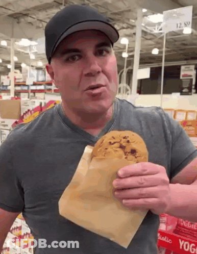A Man Eating A Cookie In Front Of A Sign That Says ' Yogi ' On It GIF