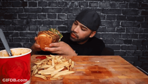 A Man Eating A Hamburger And French Fries Next To A Red Cup That Says Wendy 'S GIF