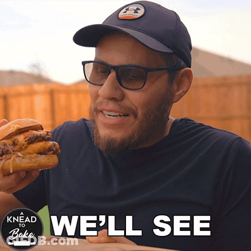 A Man Eating A Hamburger With The Words " We 'Ll See " Above Him GIF