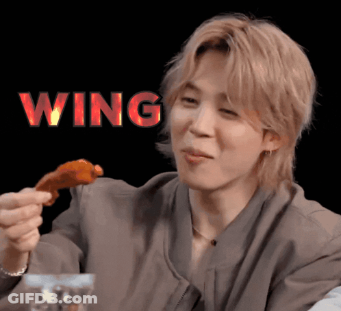 A Man Eating A Piece Of Chicken With The Word Wing Above Him GIF