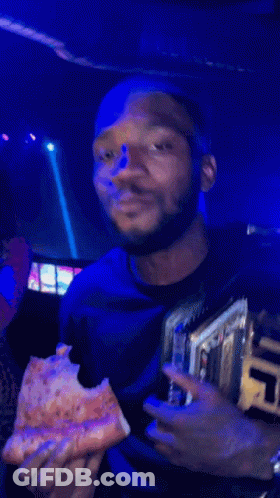 A Man Eating A Slice Of Pizza While Wearing A Ufc Championship Belt GIF