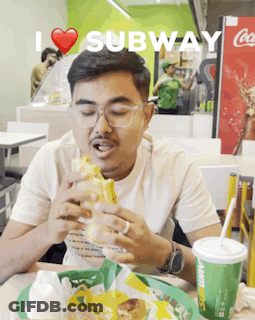 A Man Eating A Subway Sandwich And Drinking A Soda GIF