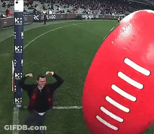 A Man Flexes His Muscles In Front Of A Giant Football GIF