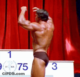 Man Flexing Muscles In Front Of Podium GIF
