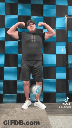 A Man Flexing His Muscles In Front Of A Checkered Wall GIF