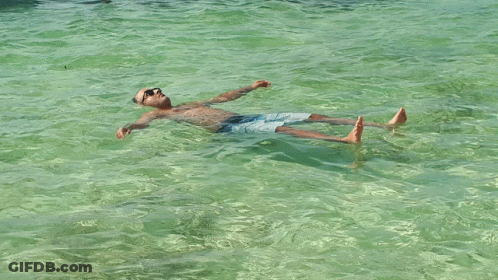 A Man Floating On His Back In The Water GIF