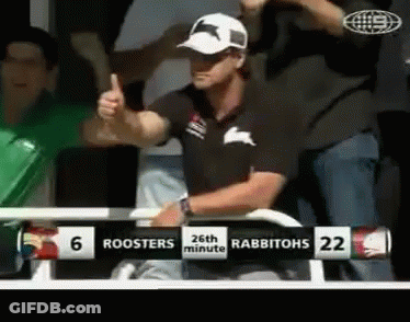 A Man Gives A Thumbs Up In Front Of A Scoreboard That Says Roosters 26Th Minute Rabbitohs 22 GIF