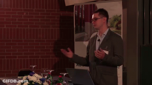 A Man Giving A Presentation In Front Of A Sign That Says ' Bs ' GIF