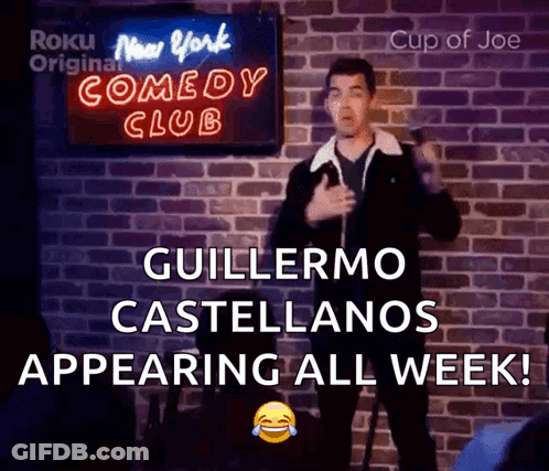 A Man Giving A Speech In Front Of A Sign That Says New York Comedy Club GIF