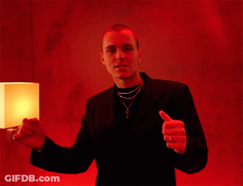 A Man Giving A Thumbs Up In Front Of A Lamp GIF