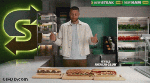 A Man Giving A Thumbs Up In Front Of Subway Sandwiches GIF
