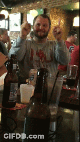 A Man Giving The Middle Finger While Sitting At A Table With Beer Bottles GIF