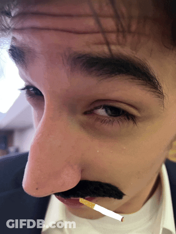 A Man Has A Fake Mustache And A Cigarette In His Mouth GIF