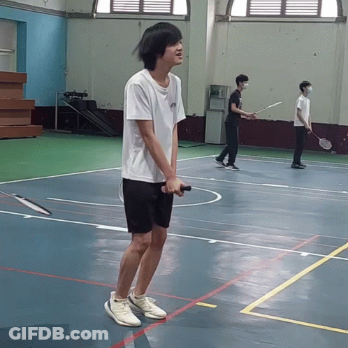 A Man Holding A Badminton Racquet On A Court GIF