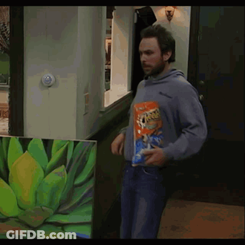 A Man Holding A Bag Of Cheetos In Front Of A Picture Of A Plant GIF