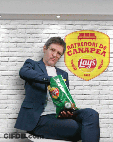 A Man Holding A Bag Of Lays Chips In Front Of A Brick Wall GIF