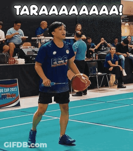 A Man Holding A Basketball And A Badminton Racket On A Court With The Words Taraaaaaaa Written Above Him GIF