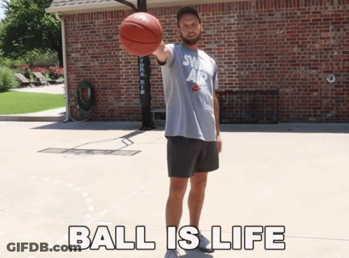A Man Holding A Basketball In Front Of A Brick Building With The Words " Ball Is Life " Below Him GIF