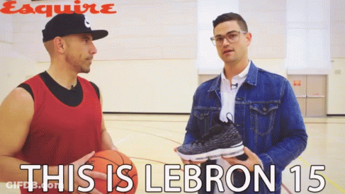 A Man Holding A Basketball Talks To Another Man Who Is Holding A Pair Of Lebron 15 Sneakers GIF