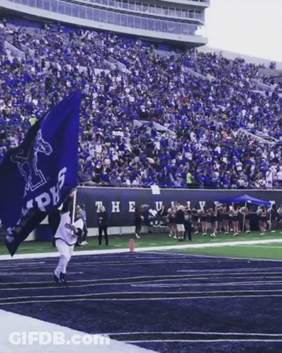 A Man Holding A Blue Flag That Says ' Alpha ' On It GIF
