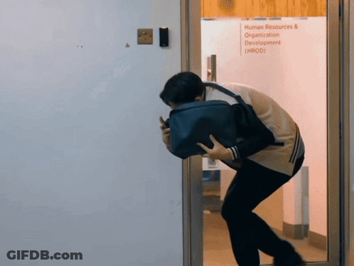 A Man Holding A Briefcase Stands In Front Of A Glass Door That Says Human Resources & Organization Development GIF