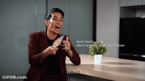 A Man Holding A Candy Bar With The Name Naim Daniel On The Bottom GIF
