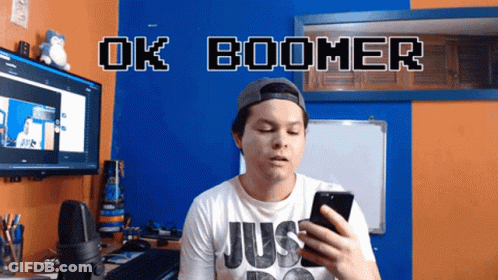 A Man Holding A Cell Phone In Front Of A Sign That Says " Ok Boomer " GIF